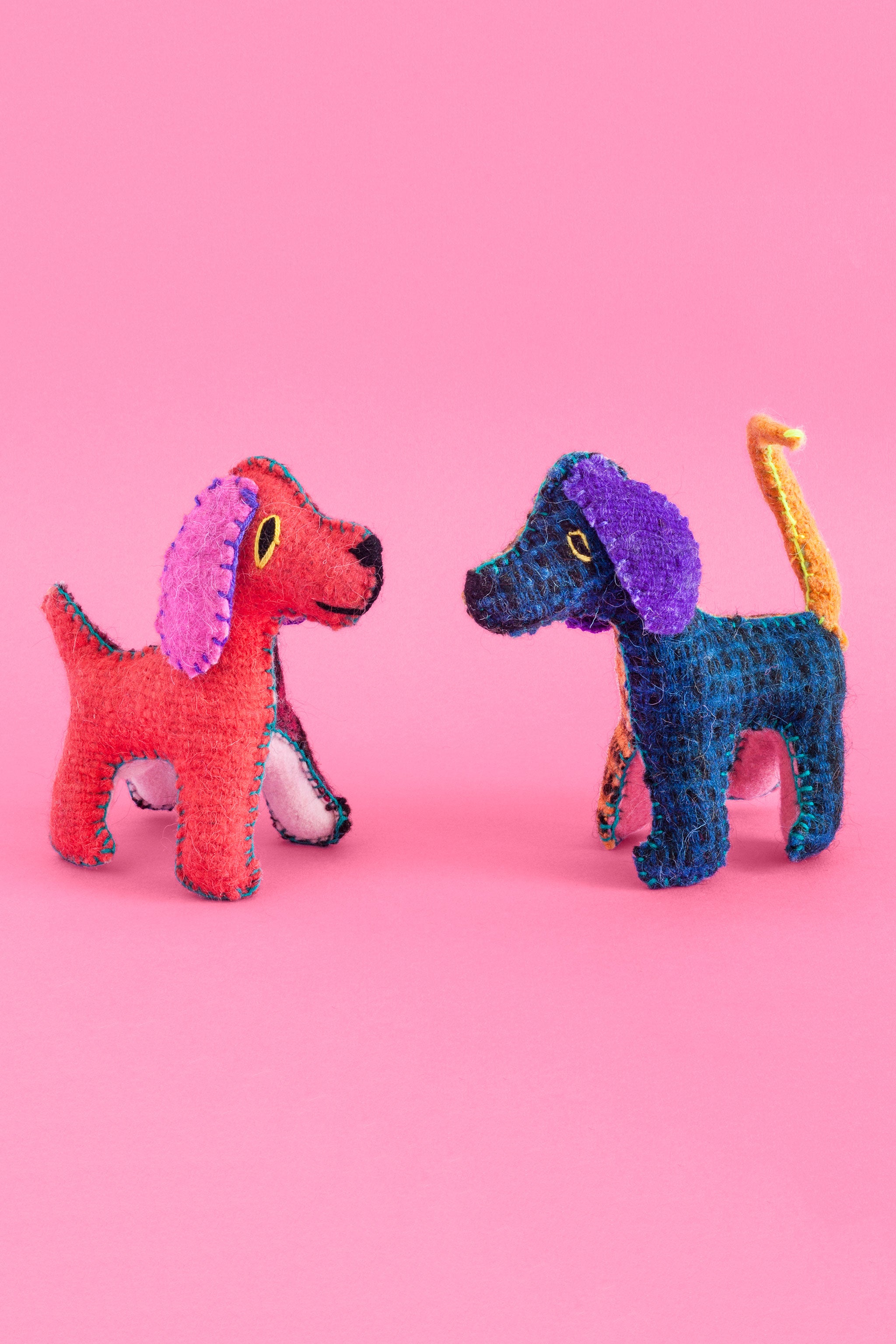 Two colorful felt dog plush toys with hand-embroidered features.