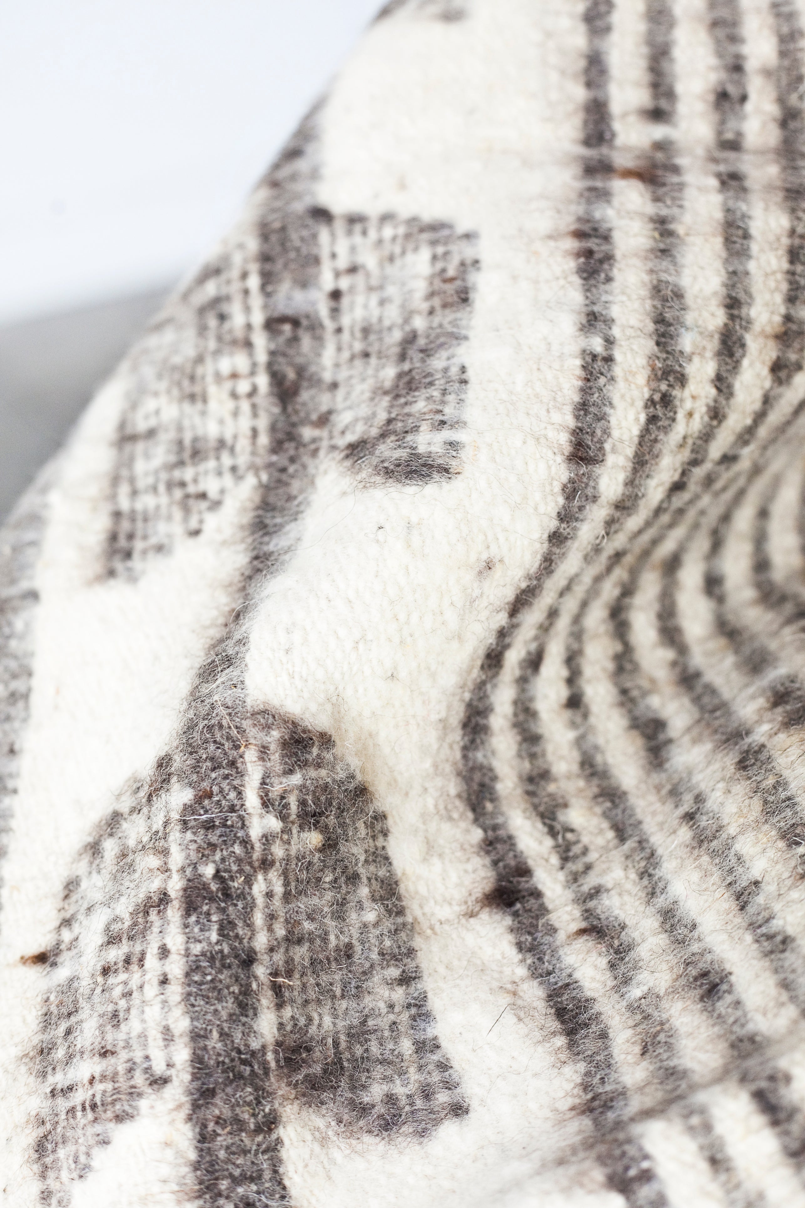 Detail of grey stripes and grey arrow motif on queen size ecru wool blanket
