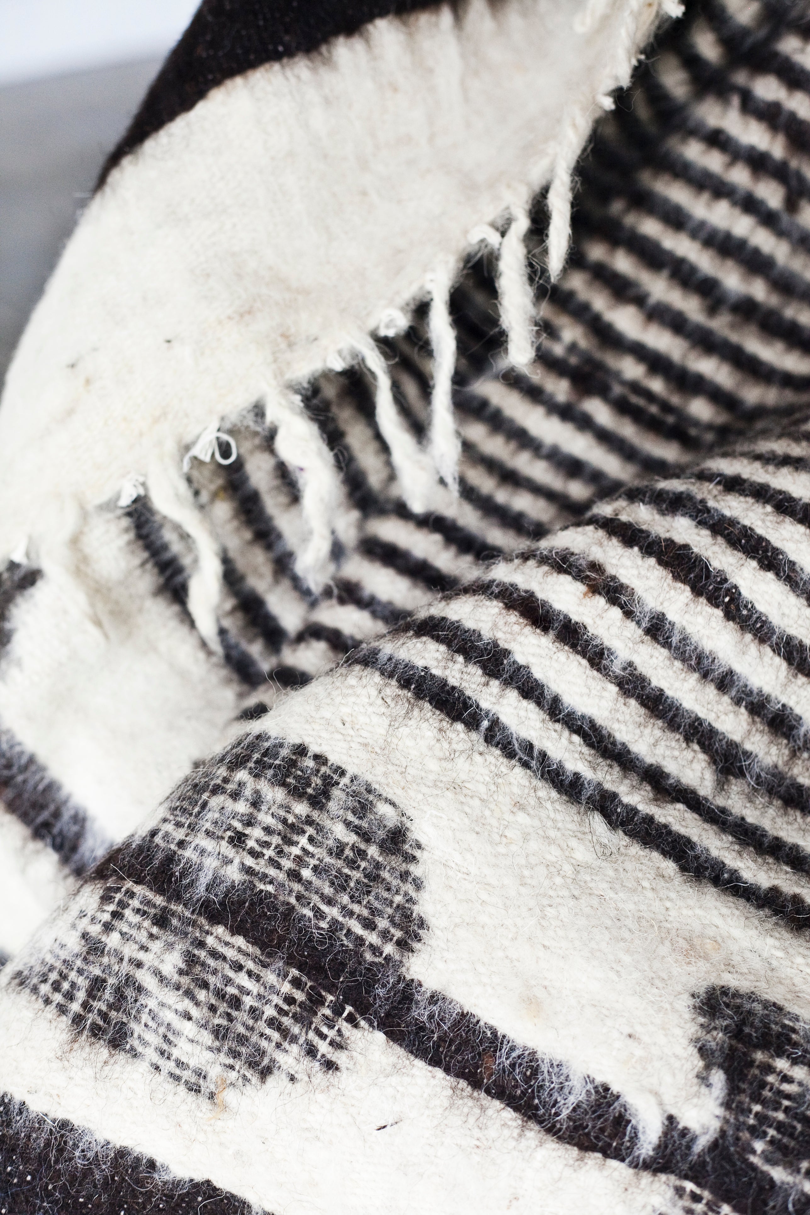 Detail of black stripes and black arrow motif on queen size ecru wool blanket