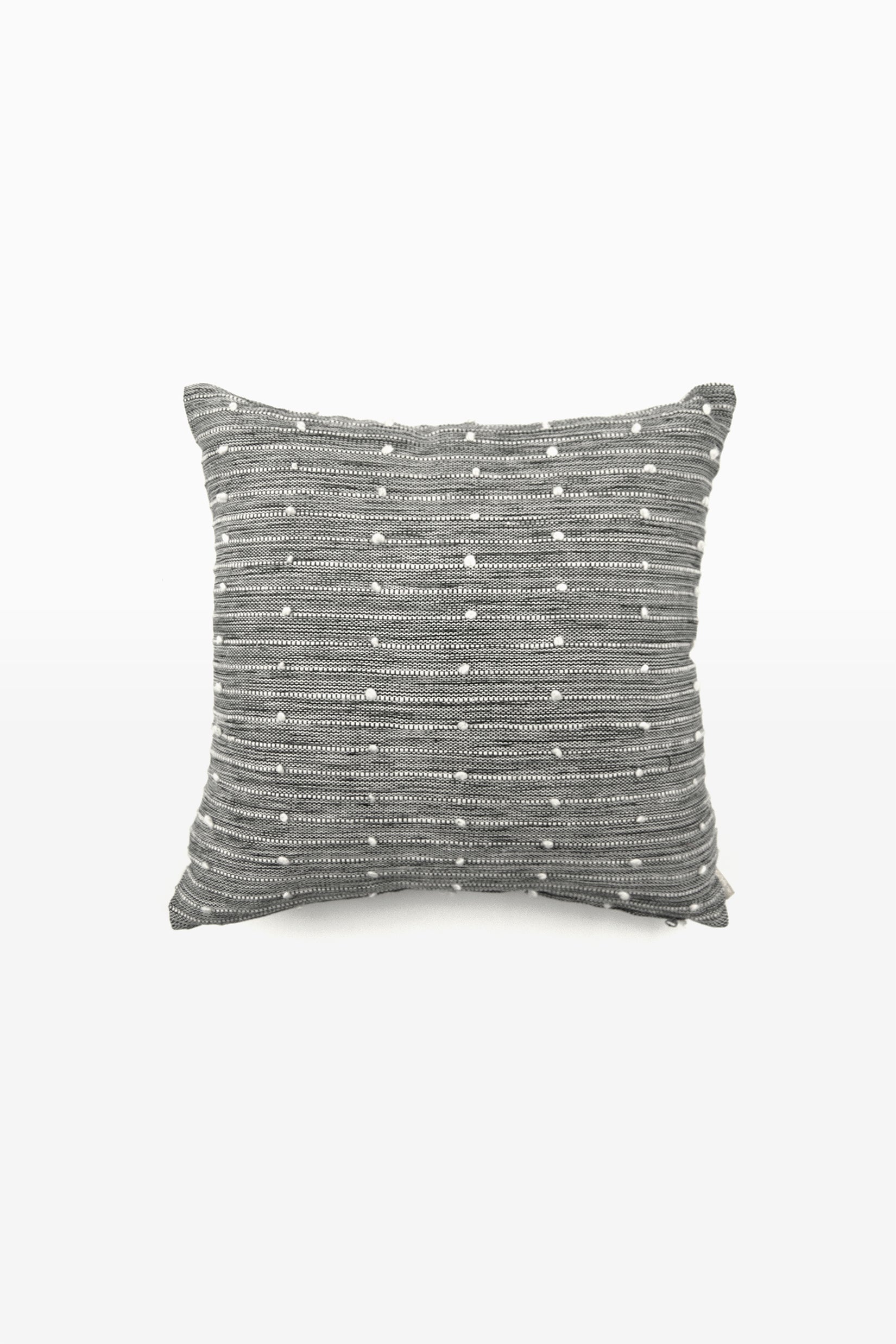 Square black and white woven throw pillow with small white pom pom accents