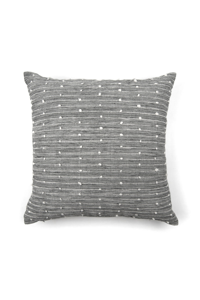 Large square black and white woven throw pillow with small white pom pom accents