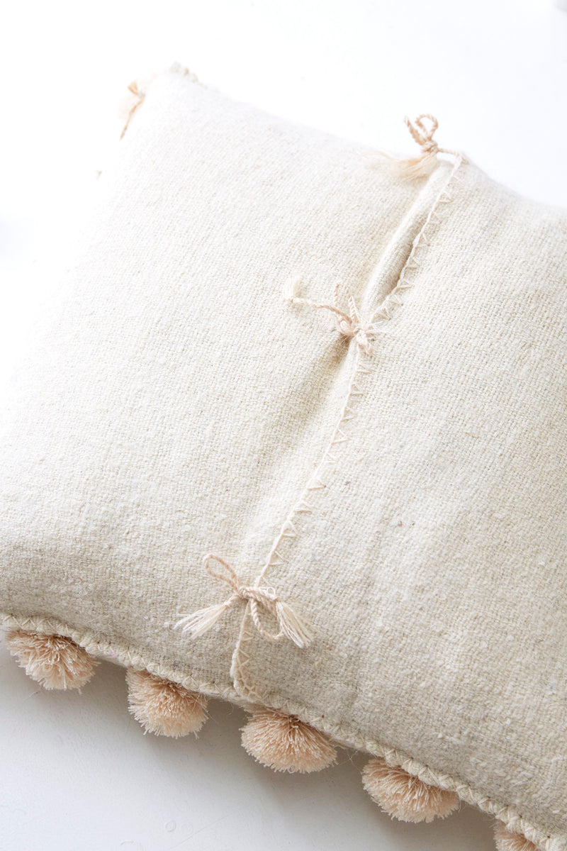 Detail of back closure ties on square woven wool cream throw pillow