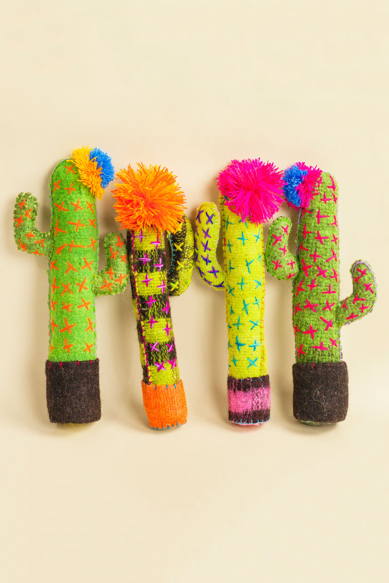 Standing felt cactus plush toys in different shades of green with hand-embroidered thorns and a colorful pom pom flower on top.
