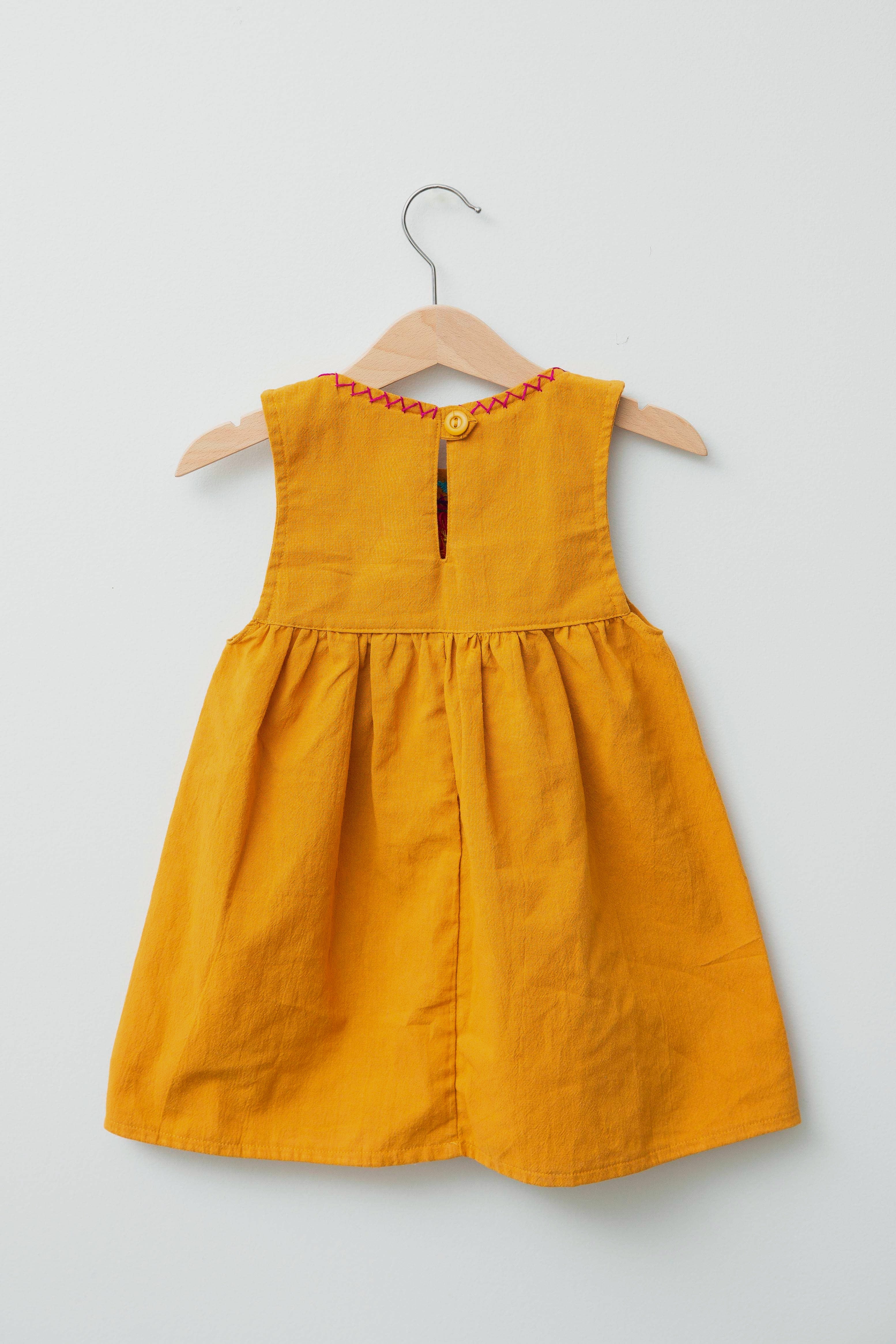 Reverse of kids sleeveless dark yellow sun dress, showing dark yellow button closure at neck.