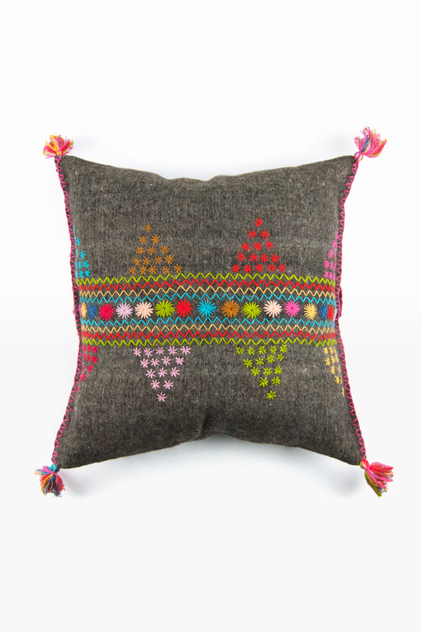 Square woven grey wool accent pillow with colorful embroidery and multicolor fringe tassels at each corner