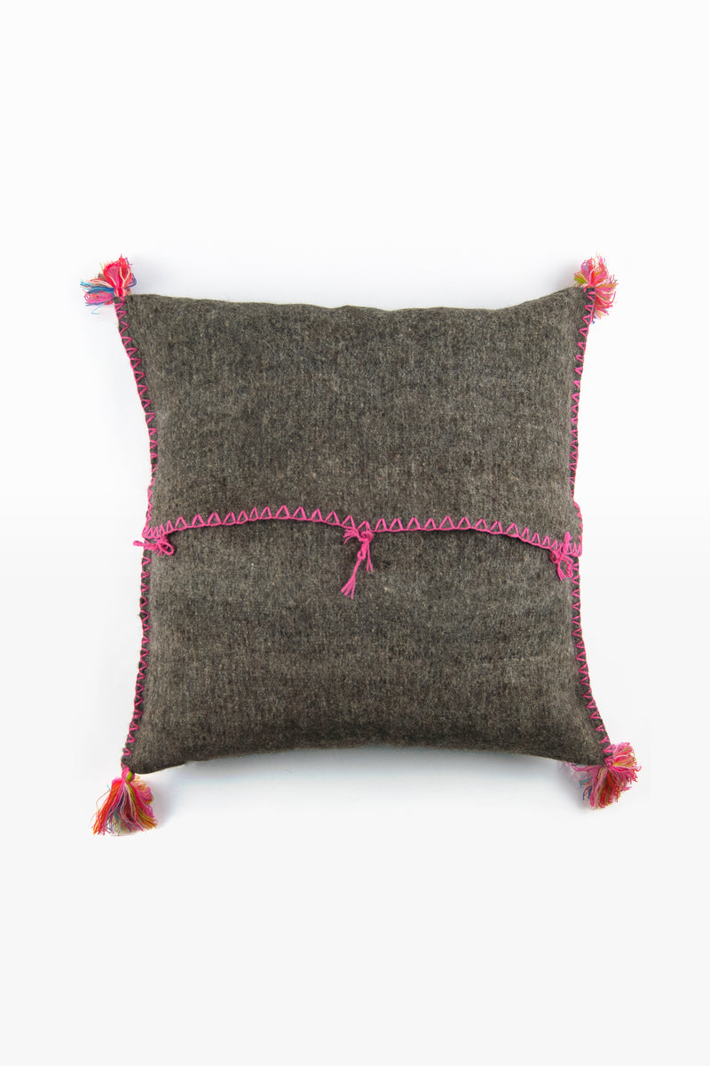 Reverse of grey square woven wool accent pillow showing back tie closures and multicolor tassels at each corner