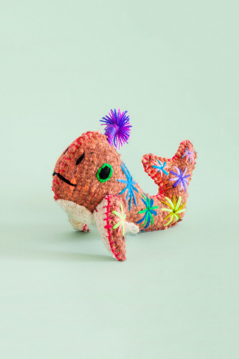 Colorful felt whale plush toy with colorful hand-embroidered star designs and features. A small stalk of braided multicolor thread is bursting out of its spout.
