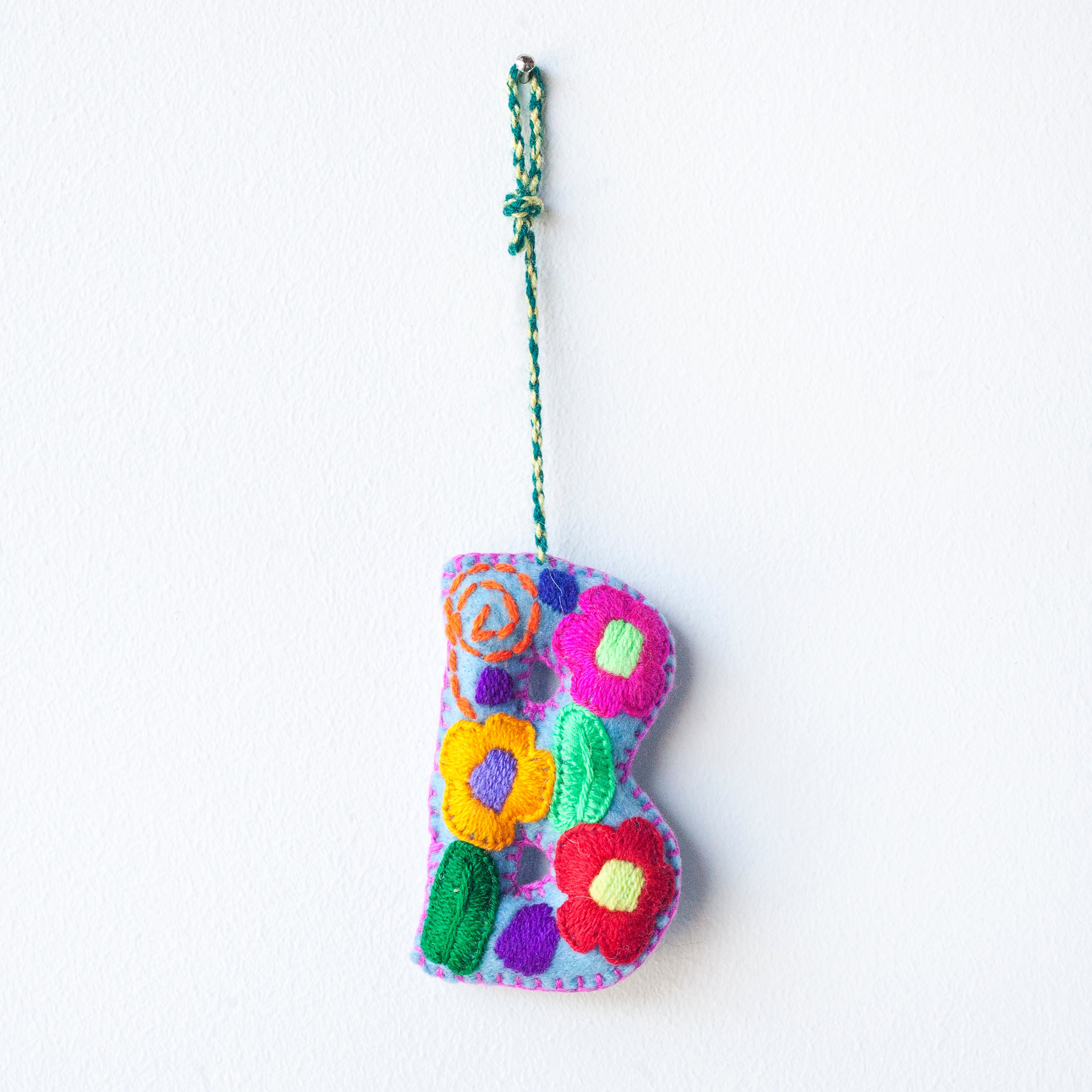 Colorful felt letter "B" with multicolor floral hand-embroidery hanging by a colorful string.