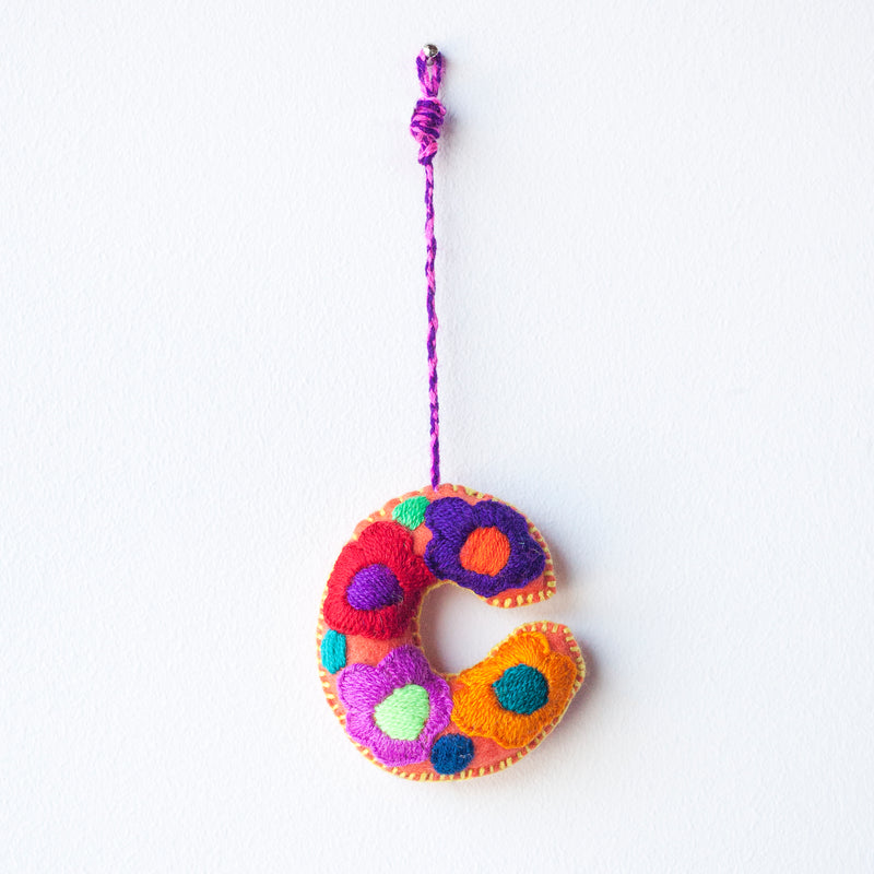 Colorful felt letter "C" with multicolor floral hand-embroidery hanging by a colorful string.