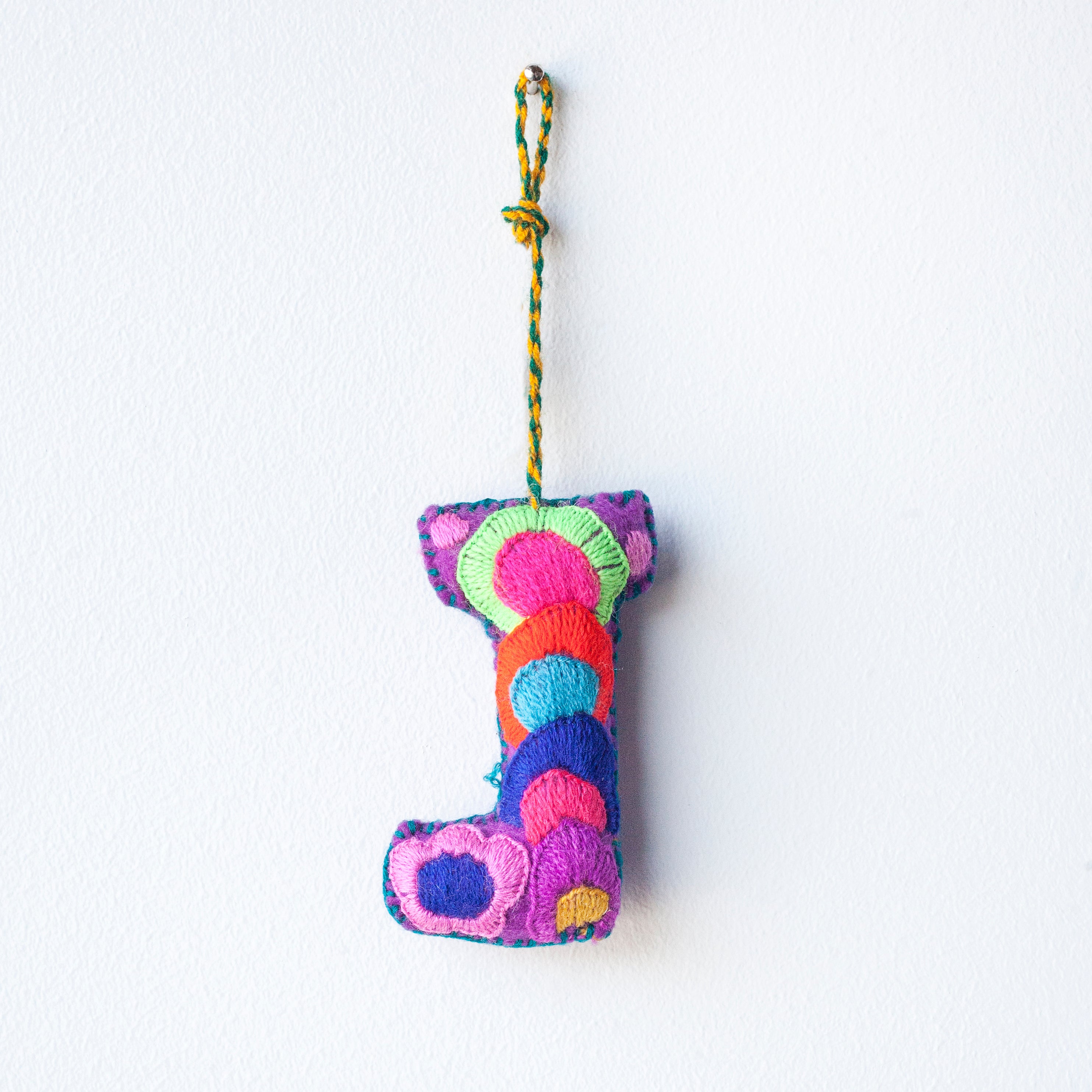 Colorful felt letter "J" with multicolor floral hand-embroidery hanging by a colorful string.