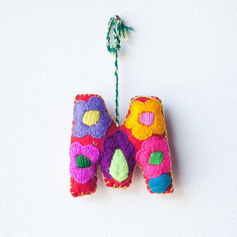 Colorful felt letter "M" with multicolor floral hand-embroidery hanging by a colorful string.