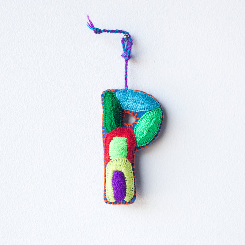 Colorful felt letter "P" with multicolor floral hand-embroidery hanging by a colorful string.