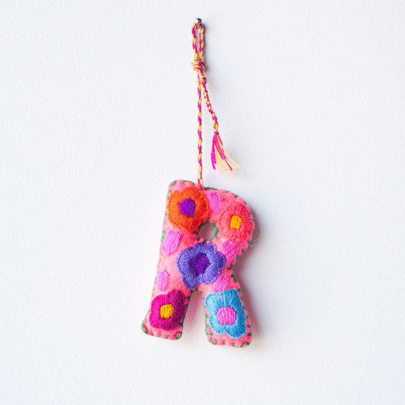 Colorful felt letter "R" with multicolor floral hand-embroidery hanging by a colorful string.