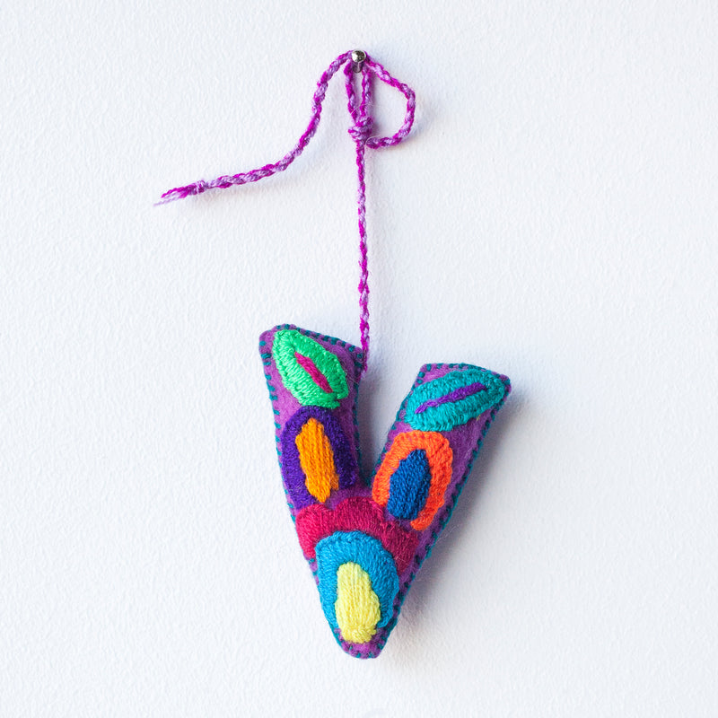 Colorful felt letter "V" with multicolor floral hand-embroidery hanging by a colorful string.