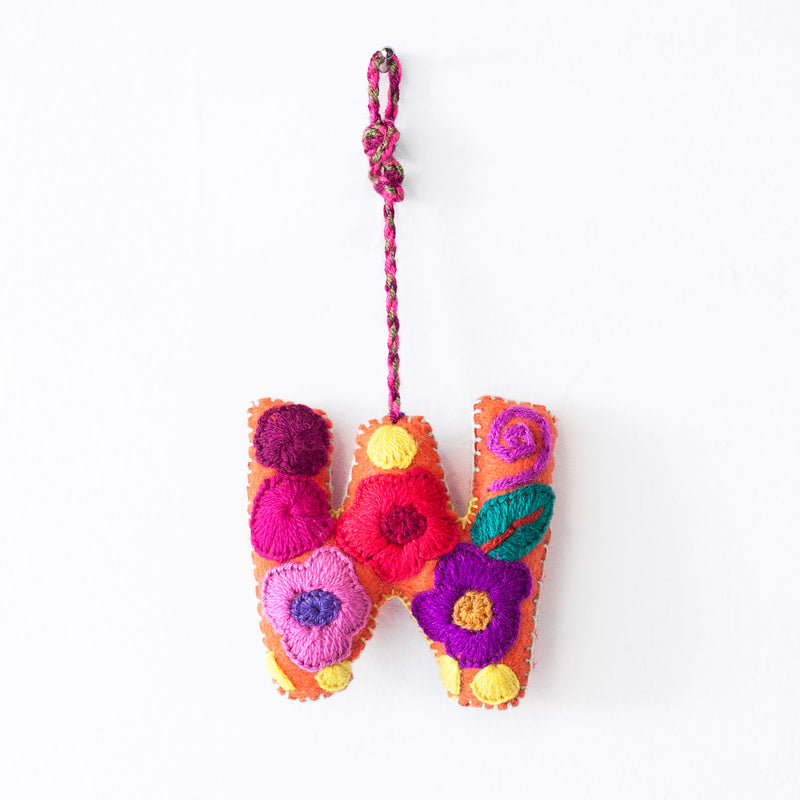 Colorful felt letter "W" with multicolor floral hand-embroidery hanging by a colorful string.