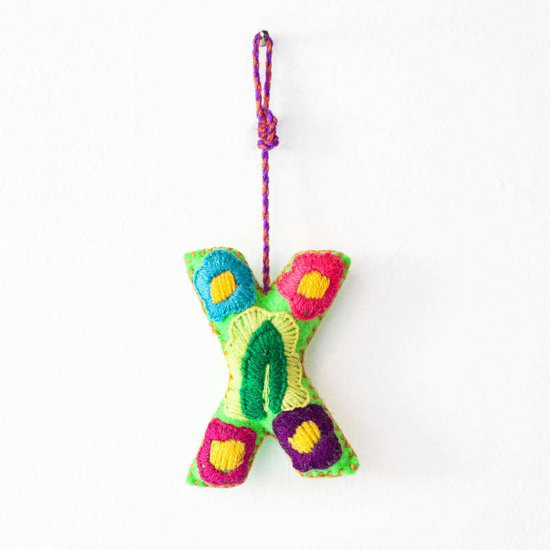 Colorful felt letter "X" with multicolor floral hand-embroidery hanging by a colorful string.