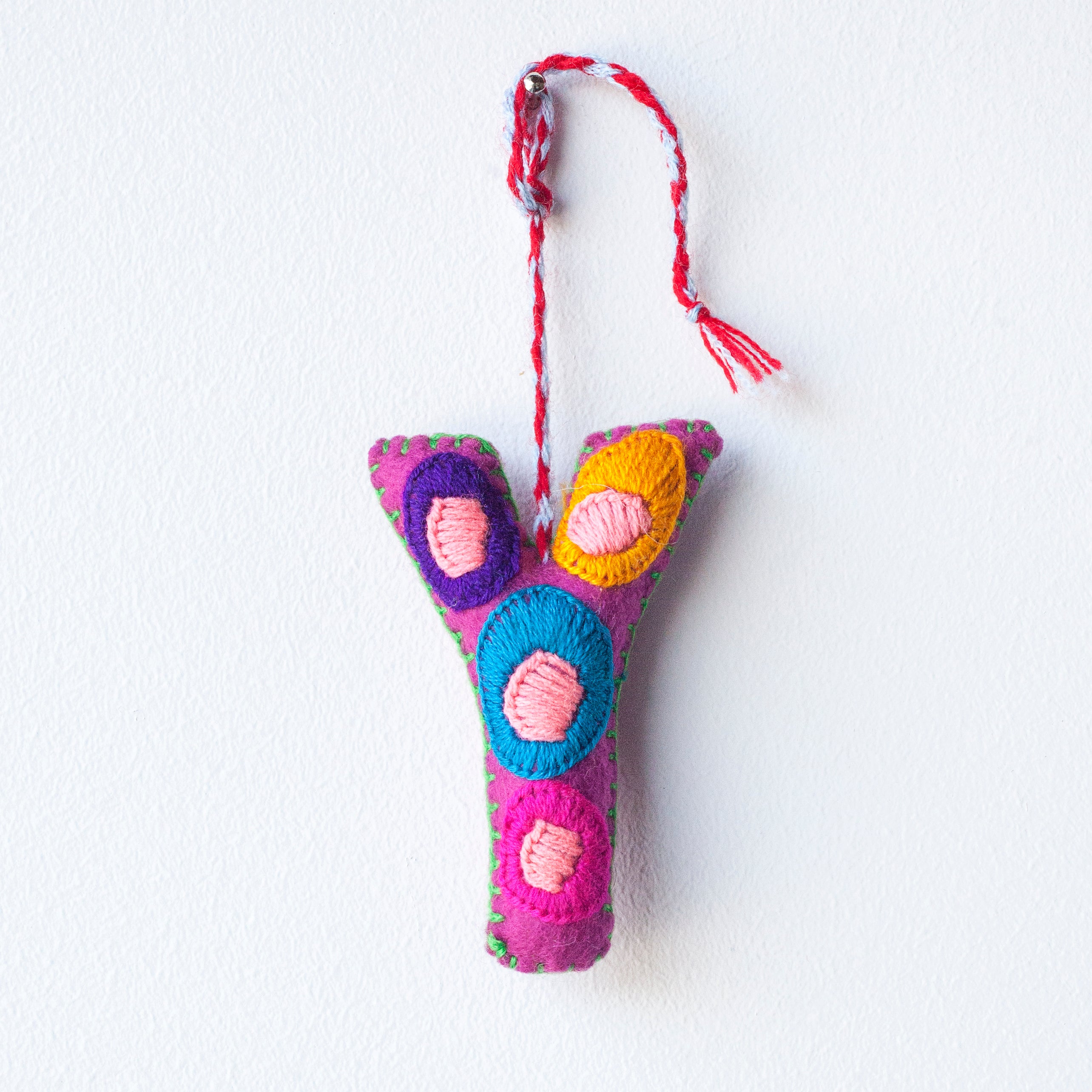 Colorful felt letter "Y" with multicolor floral hand-embroidery hanging by a colorful string.
