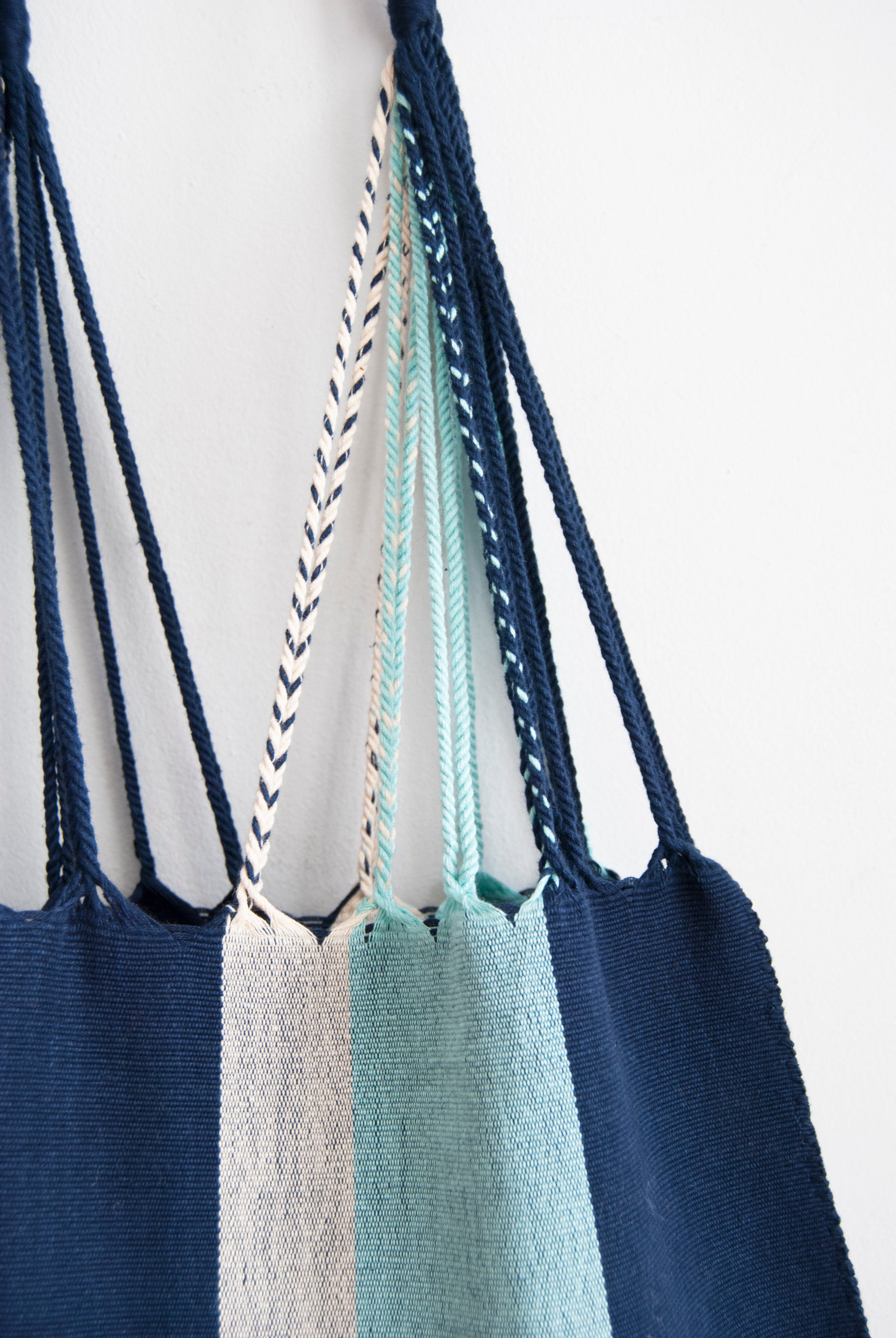 Detail showing tight weave of tote bag with vertical navy, white, and light blue stripes and braided straps.