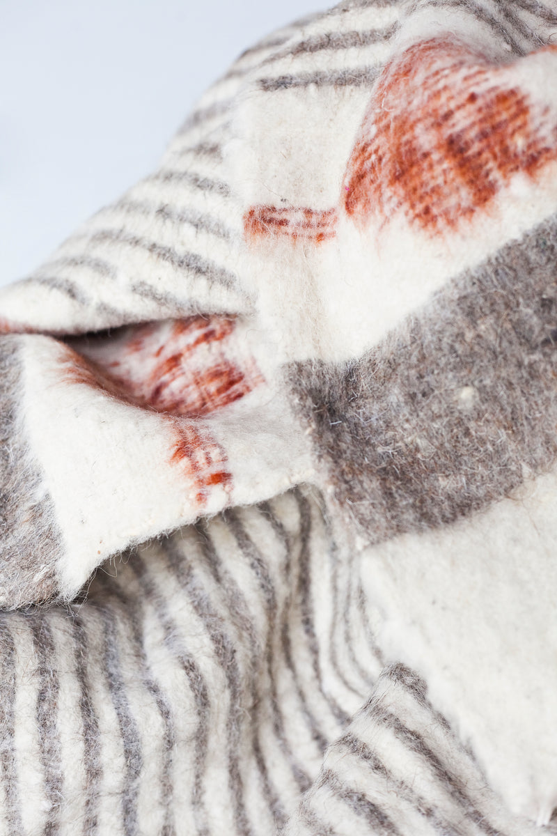 Detail of grey stripes and rust arrow motif on queen size ecru wool blanket