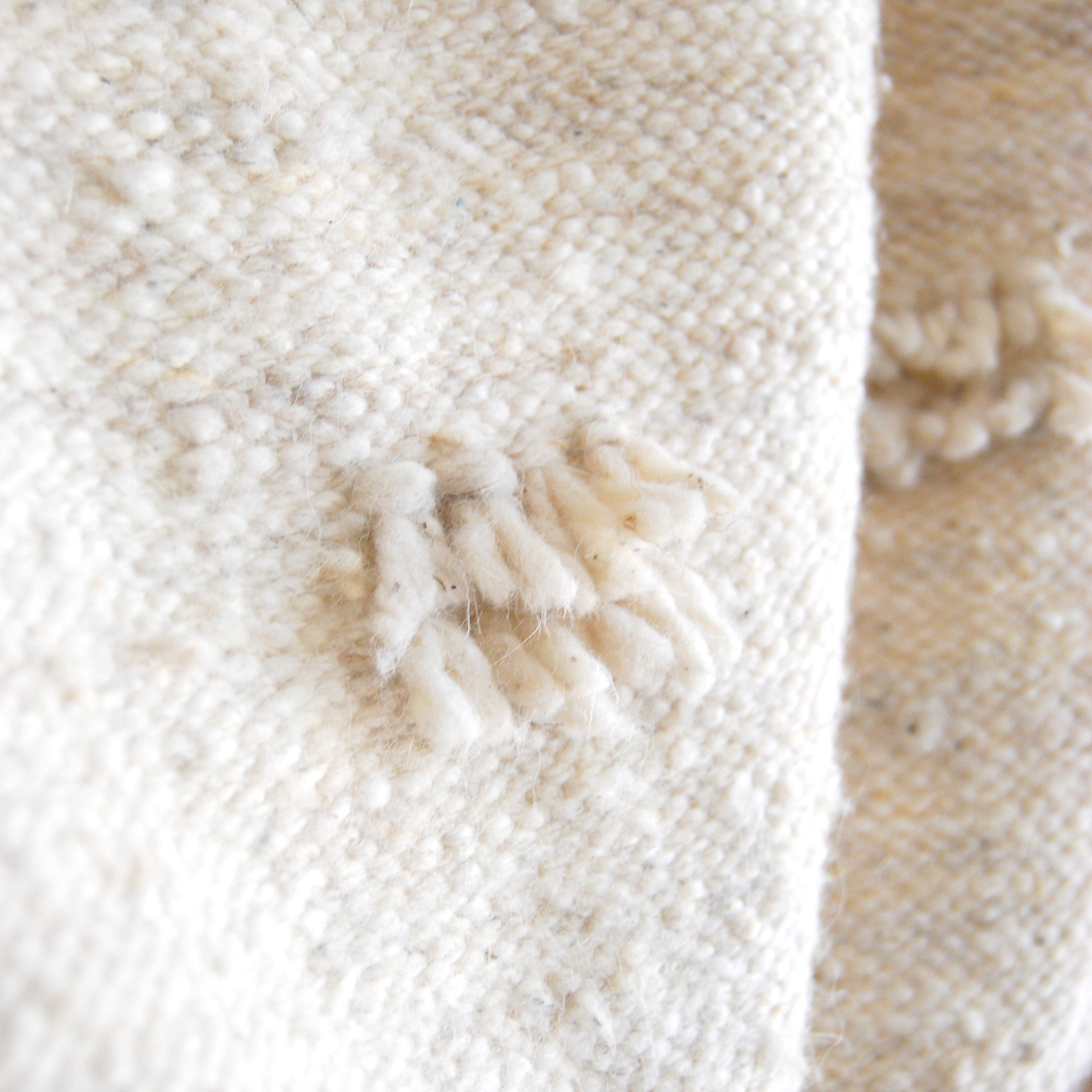 Detail of fringe accents and weave on cream wool queen size blanket