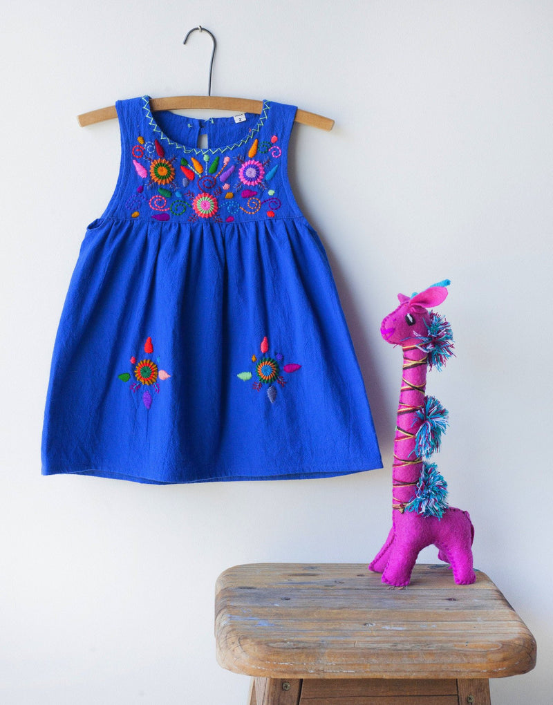Kids sleeveless royal blue sun dress hanging with multicolor hand-embroidered floral pattern on chest and two hand-embroidered flowers near the bottom of the skirt on the front left and right.