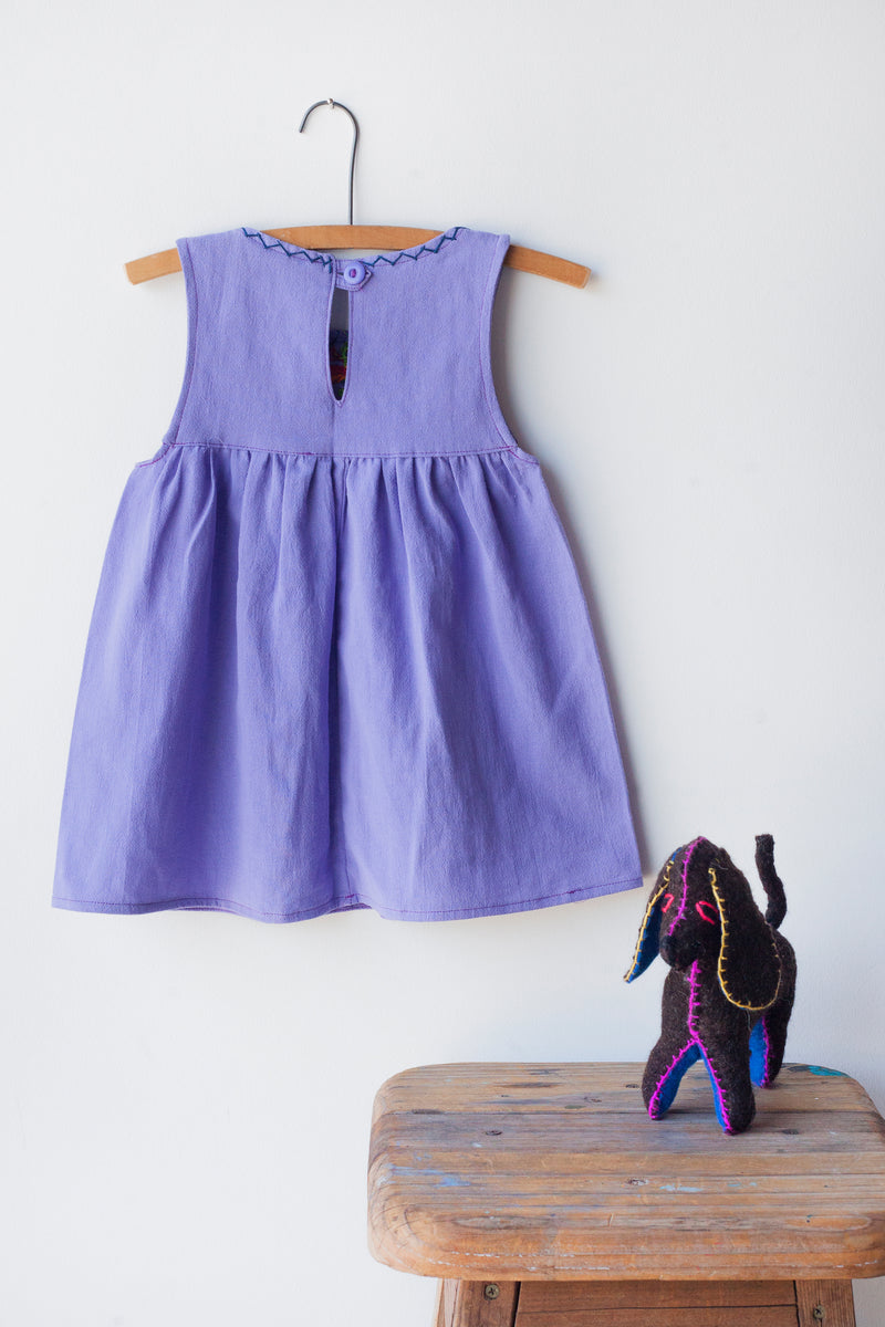 Reverse of kids sleeveless light purple sun dress, showing light purple button closure at neck.