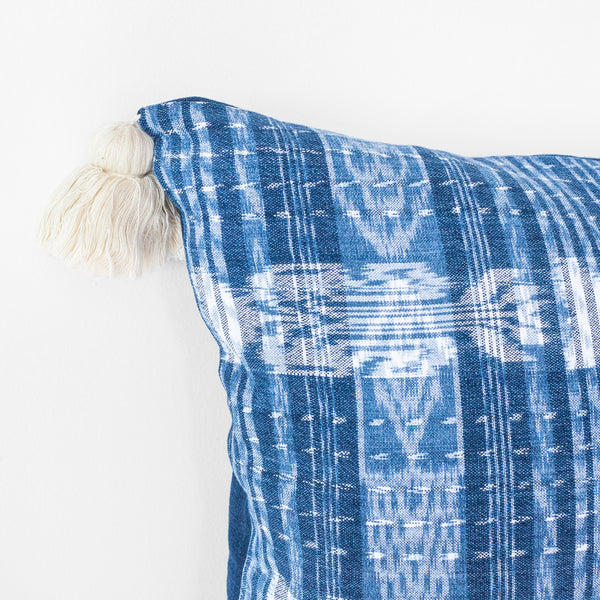 Detail of white tassels at corner of blue and white textile square pillow