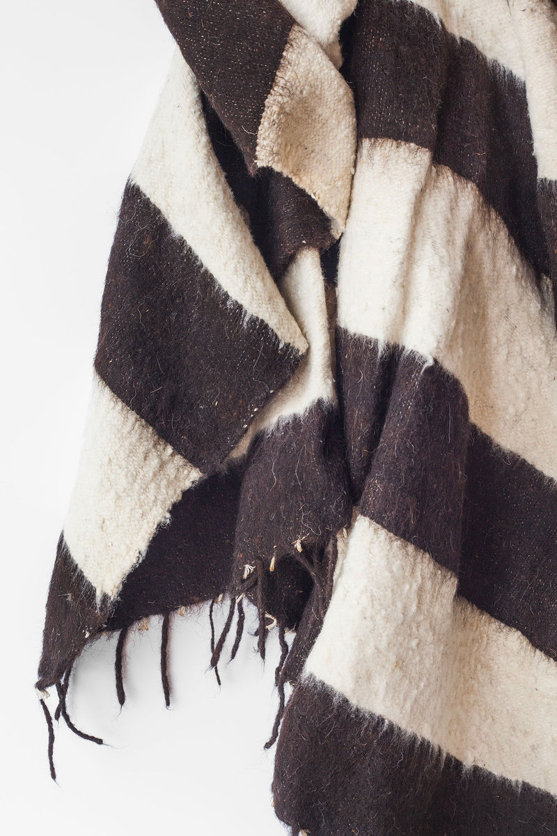 Detail of thick black stripes and tied tassels on queen size ecru wool blanket