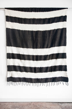 Queen sized ecru wool blanket with rows of thick horizontal black stripes and a row of tied tassels at each end