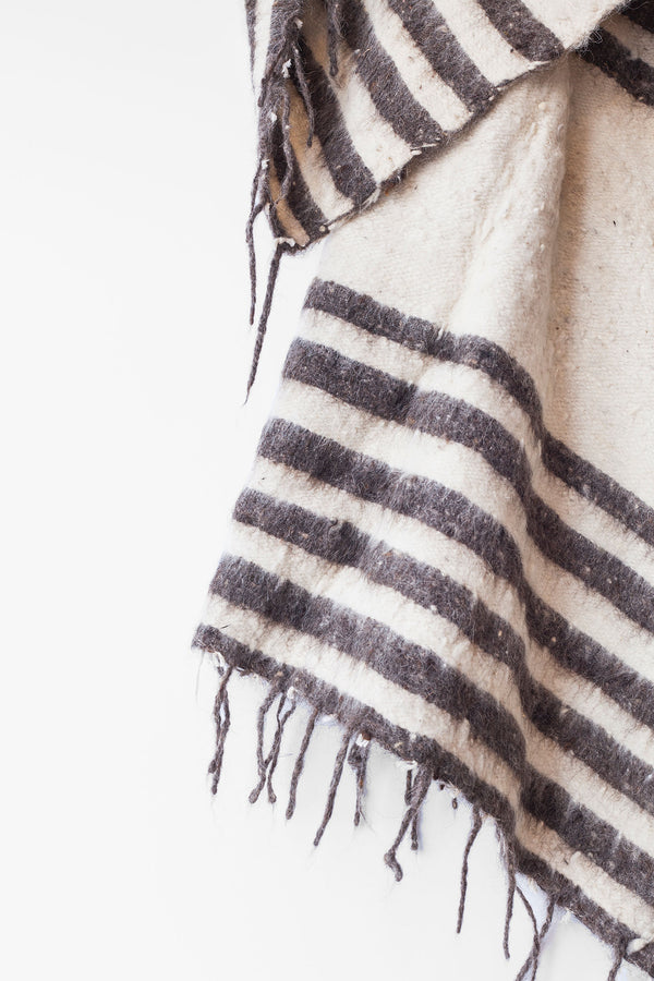 Detail of grey stripes and tied tassels on queen size ecru wool blanket