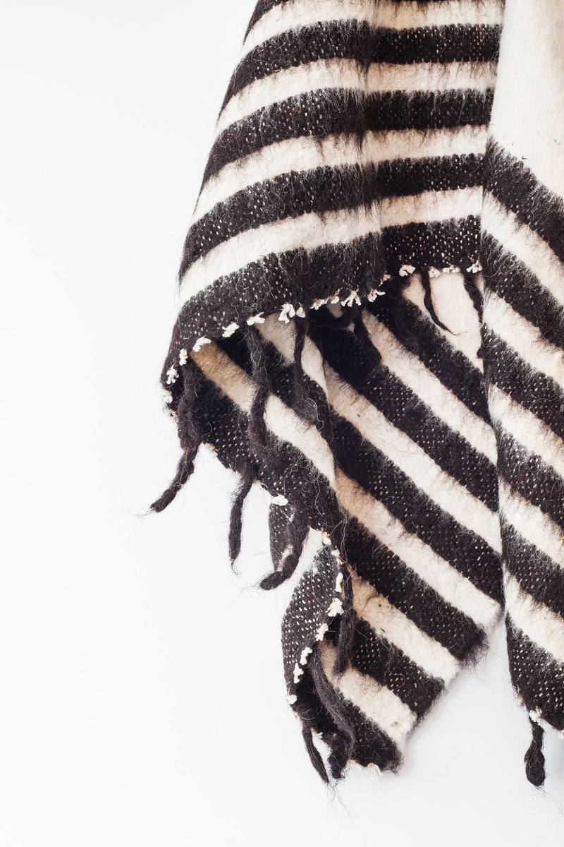 Detail of black stripes and tied tassels on queen size ecru wool blanket