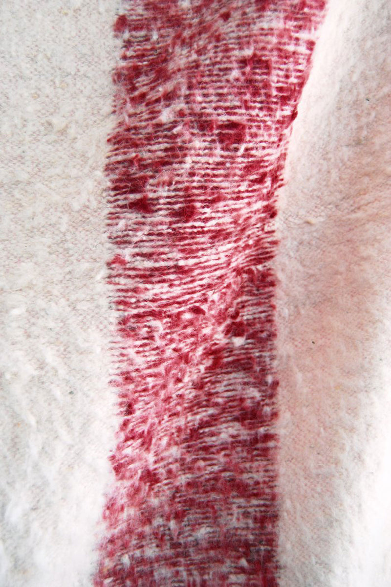 Detail of woven ecru wool blanket with wide burgundy stripe
